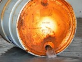 a can with a rusted top and liquid pouring out